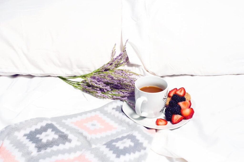 A cozy morning setup with coffee, lavender, and berries on a bed.